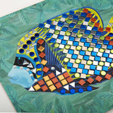 Detailed view of a colorful fish mosaic craft with shiny blue, silver, and gold stickers on a leafy background.