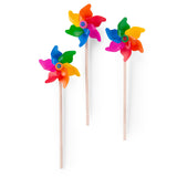 Three Moulin Roty multi-colored toy windmills with wooden sticks on a white background.