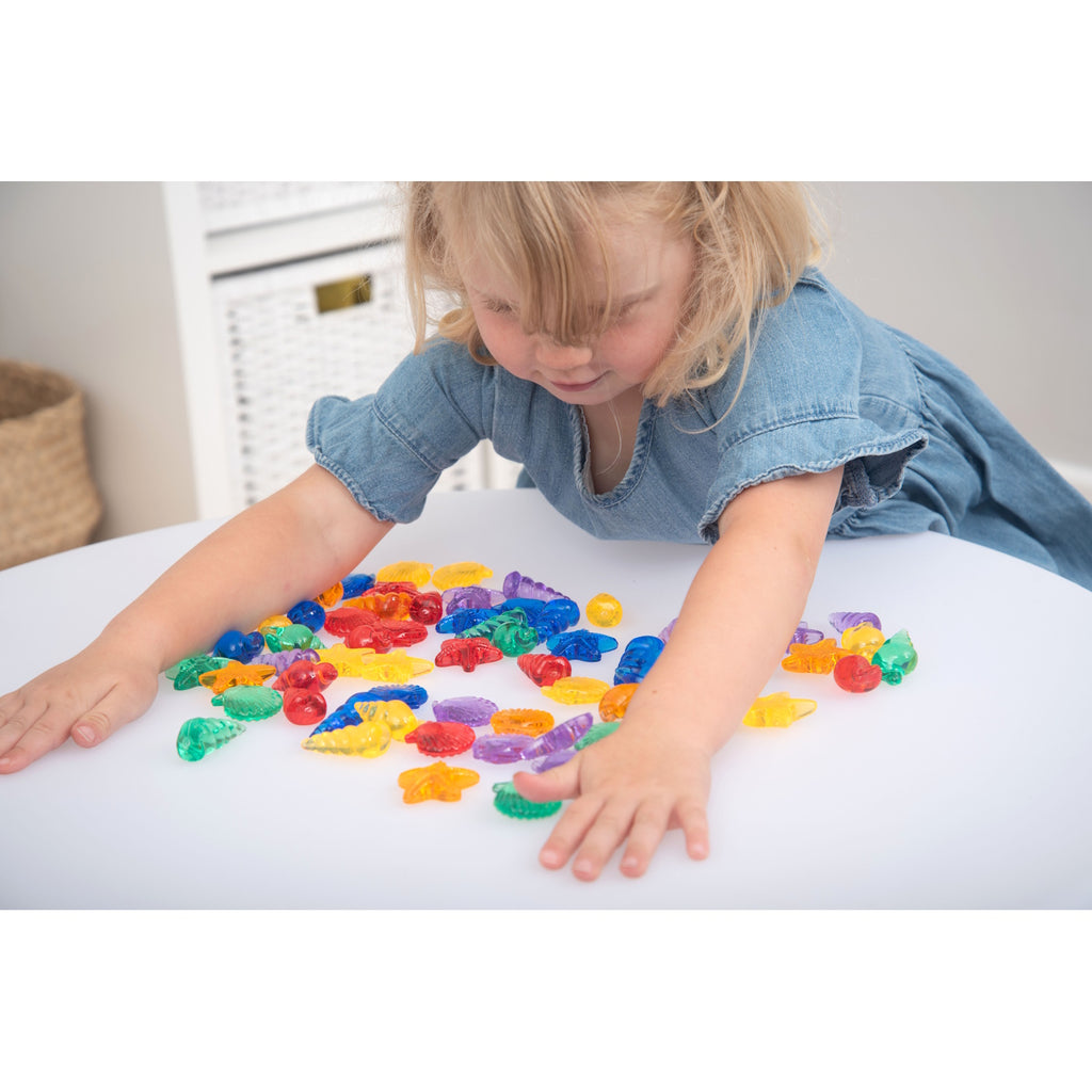 A set of vibrant, see-through plastic shells designed for sensory exploration, sorting, counting, and light-based activities.