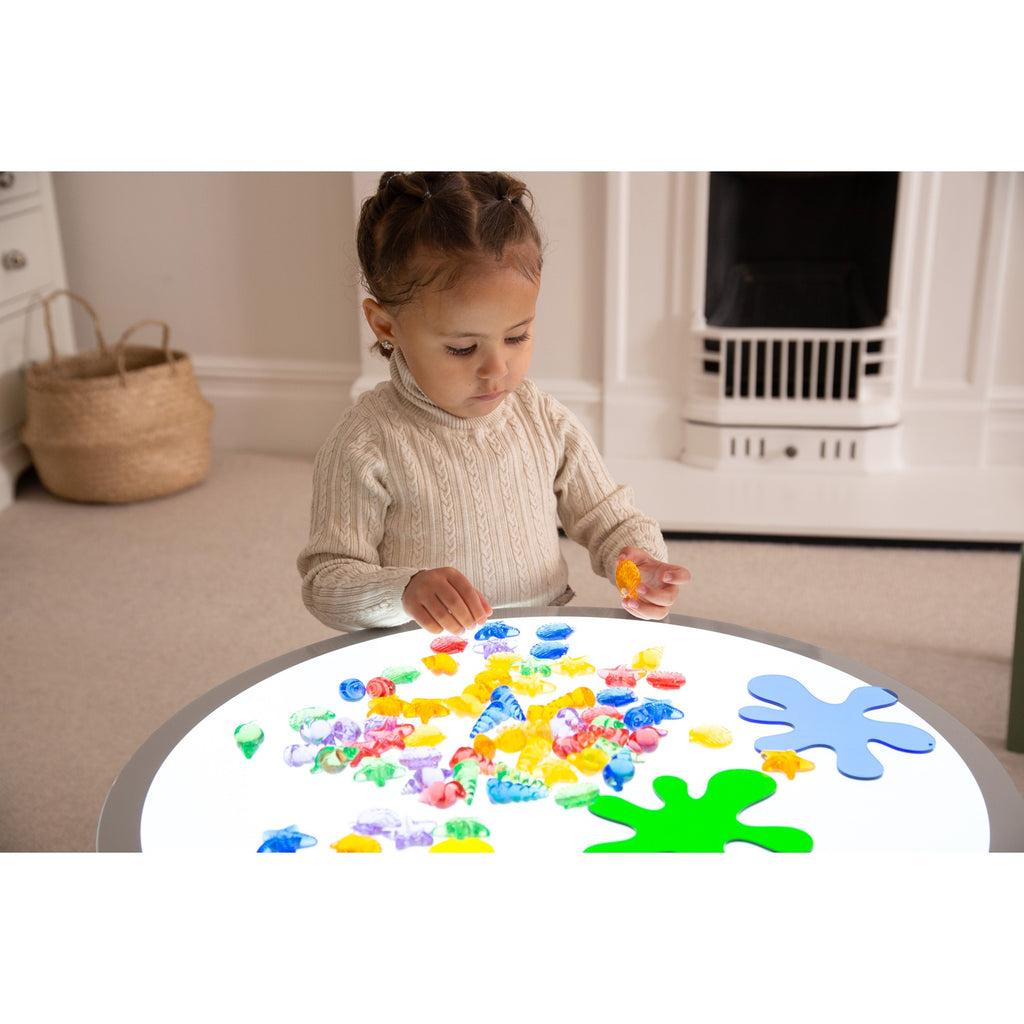 A set of vibrant, see-through plastic shells designed for sensory exploration, sorting, counting, and light-based activities.