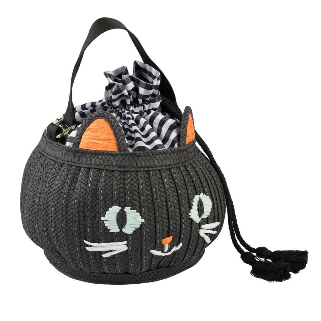 A black woven handbag with a cat face design, orange ears, and green eyes. It features a black and white checkered fabric peeking out from the top.