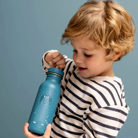 A young blond child wearing a striped sweater smiles while opening a blue cartoon triceratops water bottle.