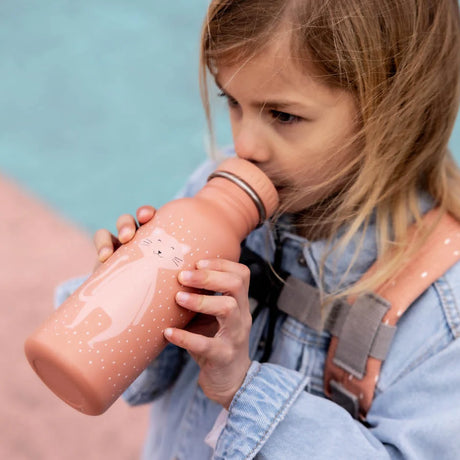 A young girl wearing a denim jacket drinks from a pink water bottle with a cute cartoon cat design.