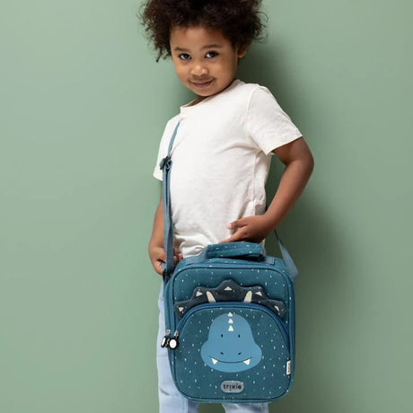 A child wearing a white T-shirt carries a teal triceratops lunch bag with a shoulder strap.