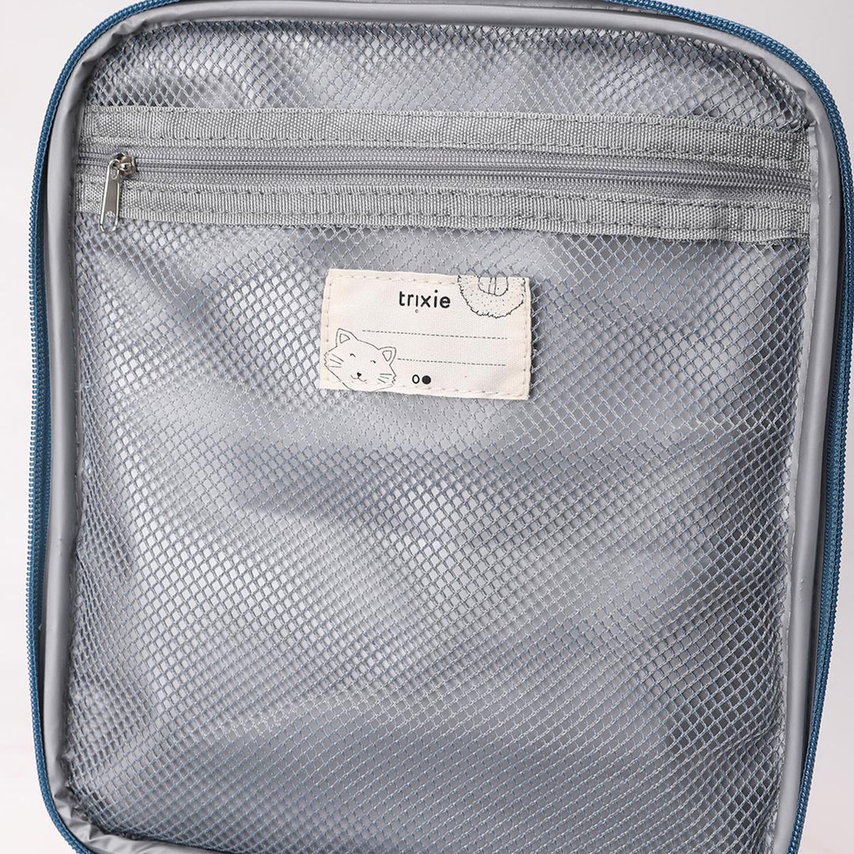 Inside of a lunch bag showing a grey zippered mesh pocket and a Trixie name tag with a cat drawing.
