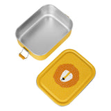 An open yellow stainless steel lunch box next to its lid featuring a cartoon lion face.