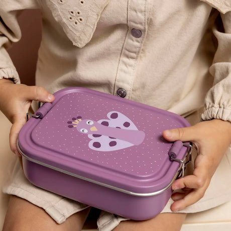 A child holds a closed purple stainless steel snack box featuring a peacock illustration on the lid.