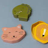 Three animal-shaped kids' lunch boxes in green dinosaur, pink cat, and yellow lion designs on a gray background.