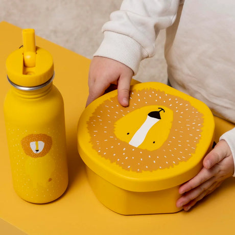 Child's hands holding a yellow lion-shaped lunch box next to a matching yellow water bottle.