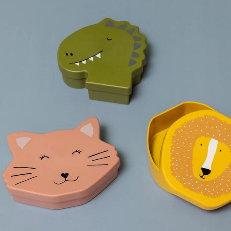 Three animal-shaped lunch boxes (dinosaur, cat, and lion) arranged on a grey background.