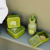Three green dinosaur-themed snack boxes and a matching water bottle on a shelf.