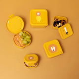An assortment of yellow lion-themed snack containers, some open with fruit and nuts, on a yellow background.
