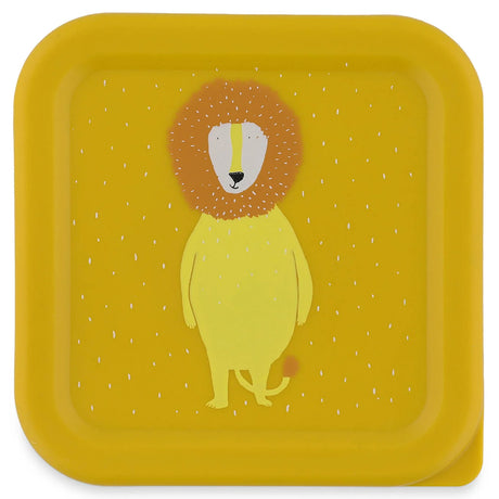 Top-down view of a square yellow snack box lid featuring a cute cartoon lion illustration with white specks.