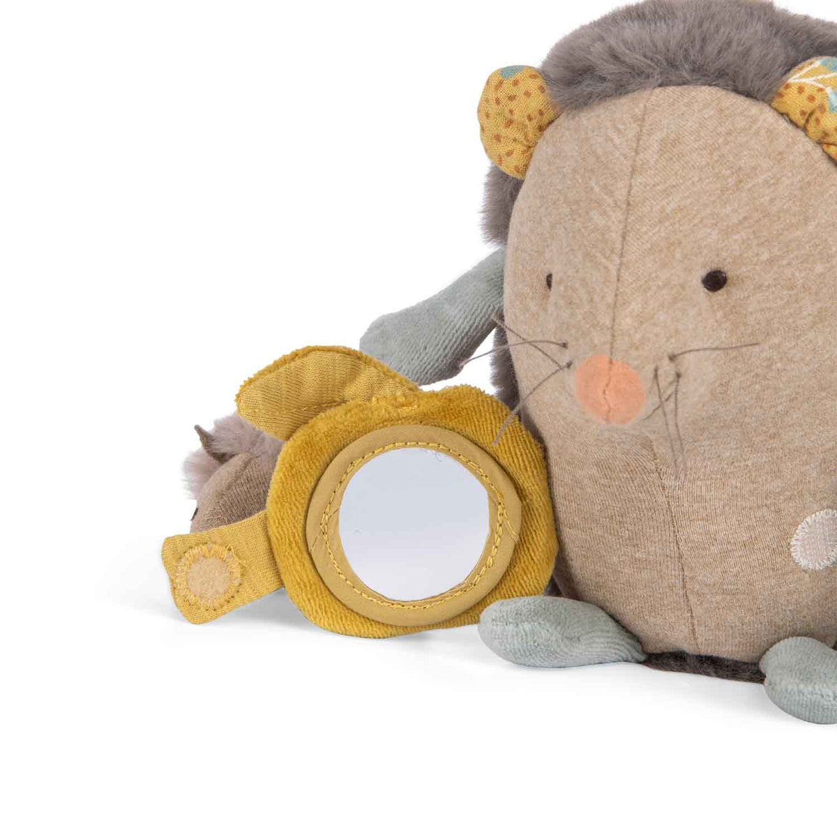 Close-up of a plush hedgehog toy with a small round mirror hidden behind a yellow fabric flap.
