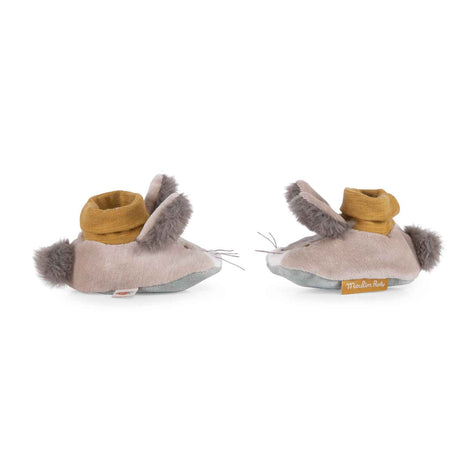 A pair of tan plush baby slippers shaped like rabbits with fuzzy ears, pom-pom tails, and mustard yellow cuffs.