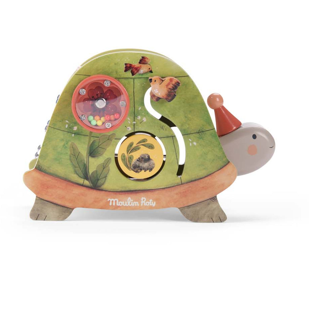 Toy turtle with green shell, featuring a rotating circular puzzle and bead-filled orange disk. The turtle wears a red party hat and smiles gently.