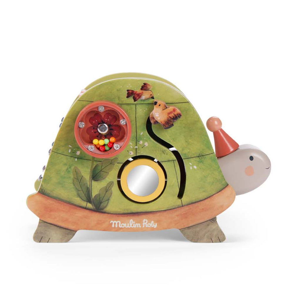 Toy turtle with green shell, featuring a rotating circular puzzle and bead-filled orange disk. The turtle wears a red party hat and smiles gently.