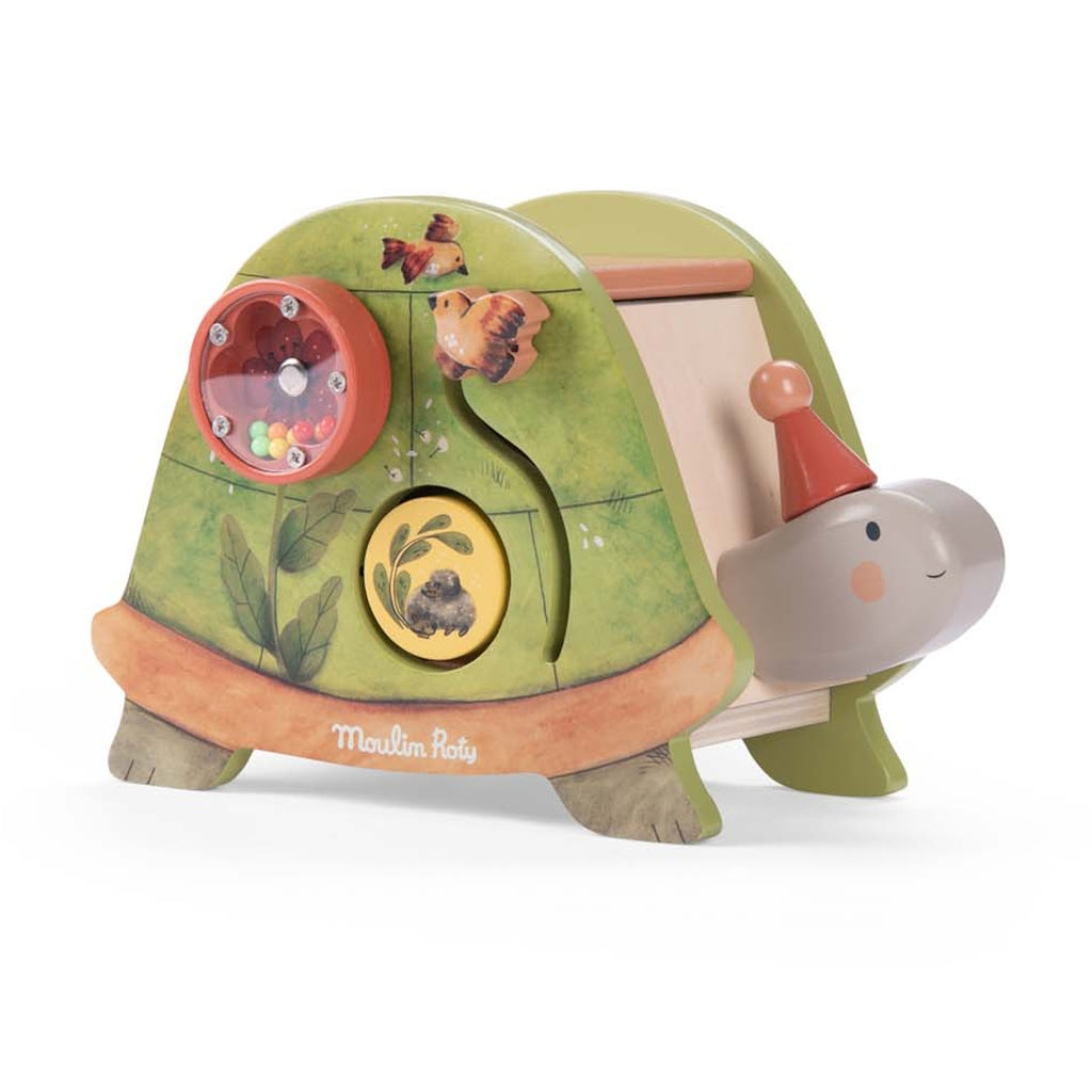 Toy turtle with green shell, featuring a rotating circular puzzle and bead-filled orange disk. The turtle wears a red party hat and smiles gently.