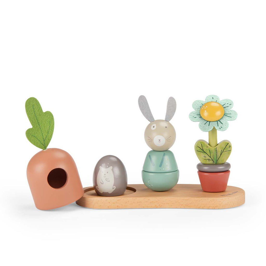 Whimsical wooden toy set featuring a rabbit, carrot, and flower on a wooden base. Each is colorful and expressive, evoking playful joy.