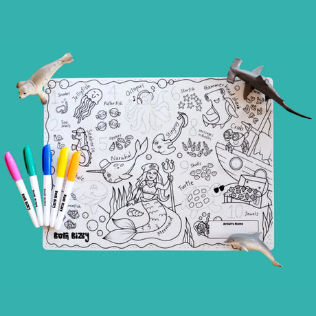 Under-the-sea children's coloring mat with marine life drawings, surrounded by colored markers and toy animals.