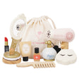 Wooden beauty play set with mirror, hair dryer, perfume, lipstick, and accessories next to a drawstring bag.