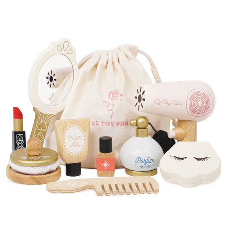Wooden beauty play set with mirror, hair dryer, perfume, lipstick, and accessories next to a drawstring bag.