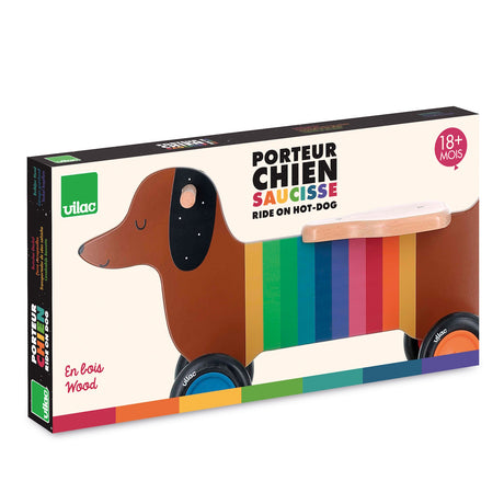 Vilac Ride On Hot-Dog: Rainbow dachshund wooden toddler walker toy for ages 18 months and up, box packaging.
