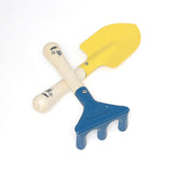 Vilac children's gardening toy set with a yellow metal trowel shovel and a blue hand rake on wooden handles.