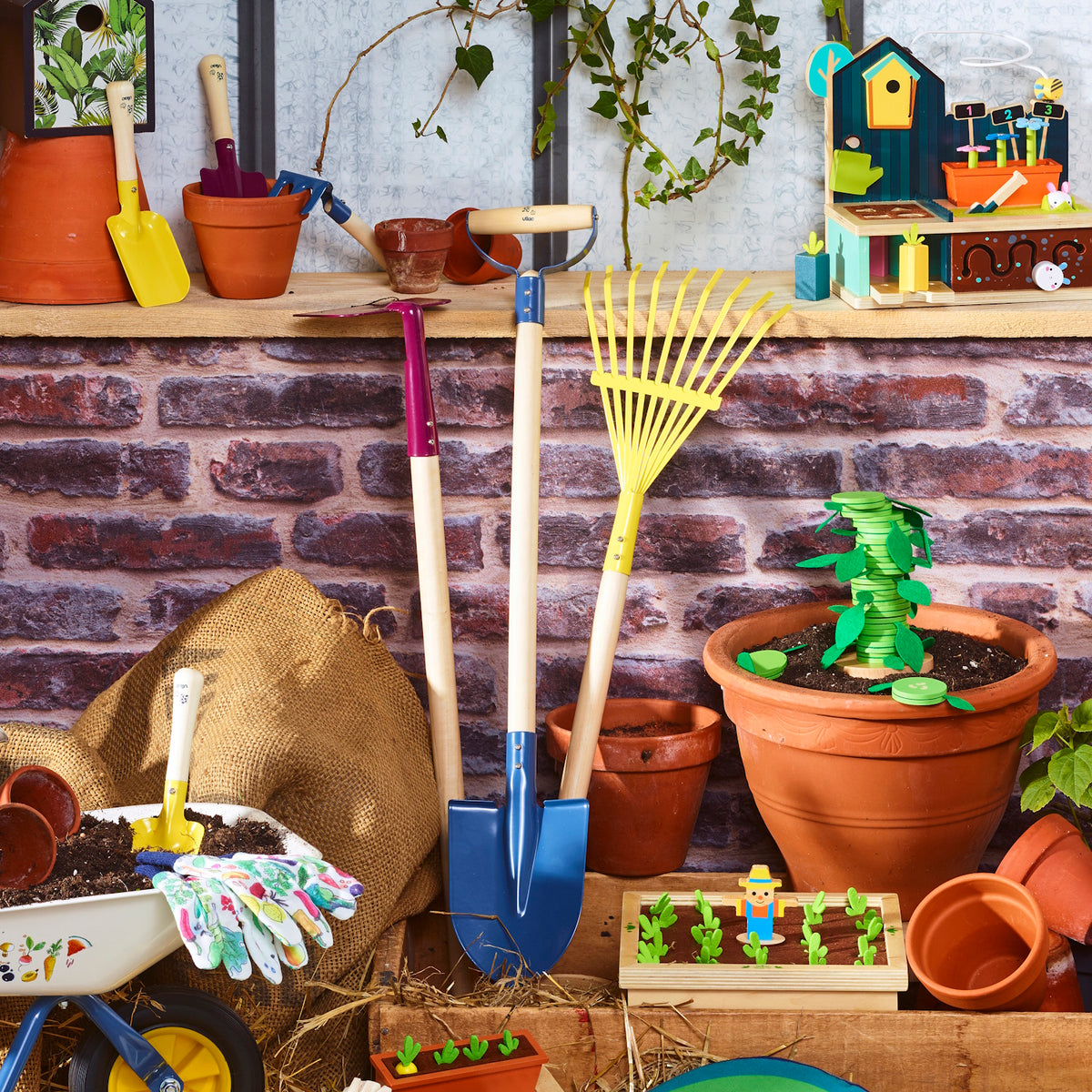 Colorful wooden kids' garden tool set with shovel, rake, and wheelbarrow displayed against a rustic brick wall.