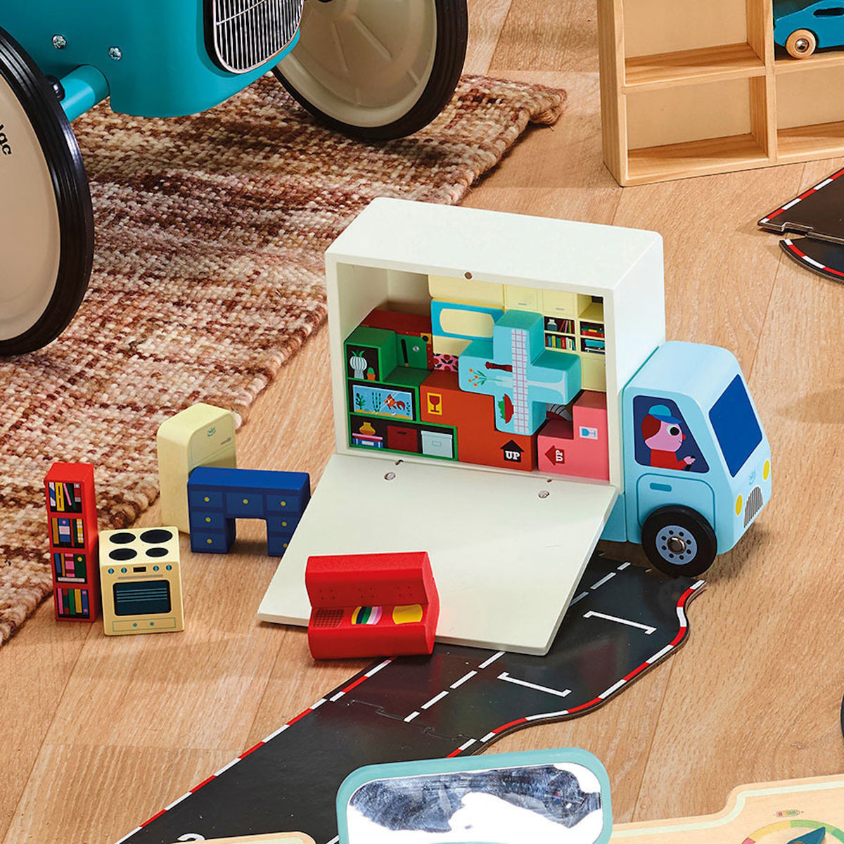 Vilac wooden moving truck toy packed with colorful household furniture blocks on a playroom floor.