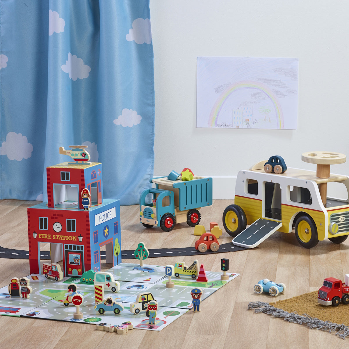Wooden rescue station play set with toy fire truck, ambulance, police station, and mat.