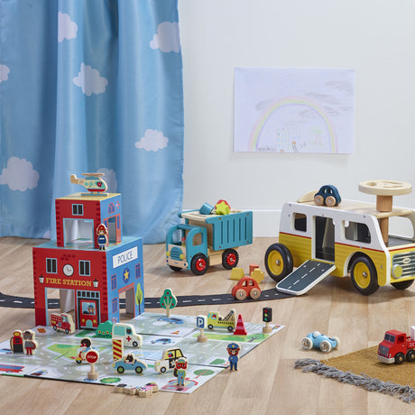 Wooden rescue station play set with toy fire truck, ambulance, police station, and mat.