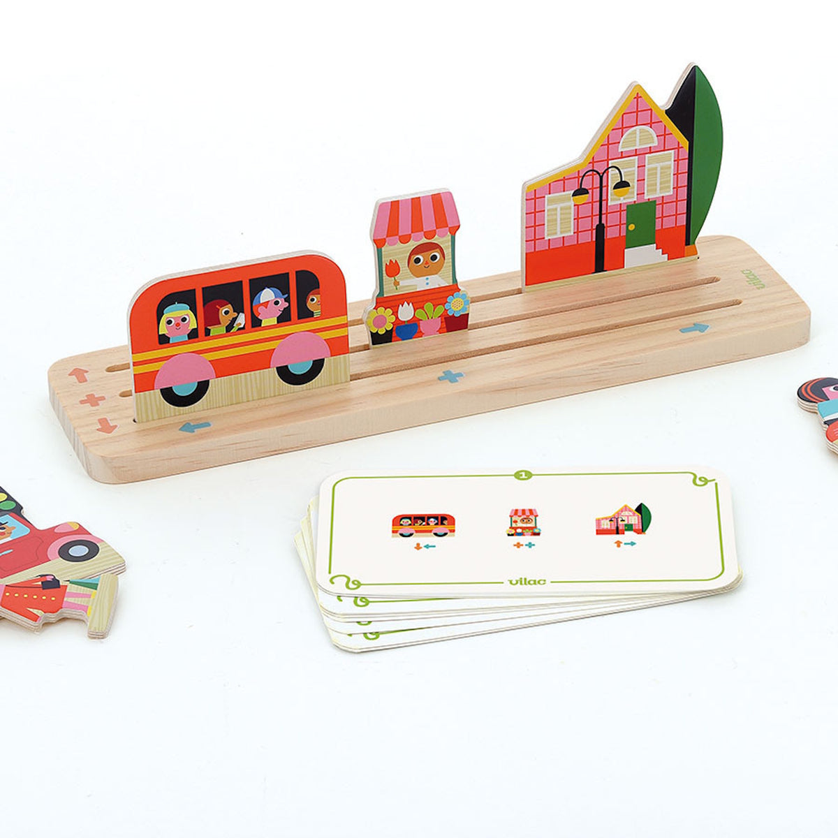 Vilac wooden educational game showing a toy bus, flower shop, and house placed on a slotted base with cards.