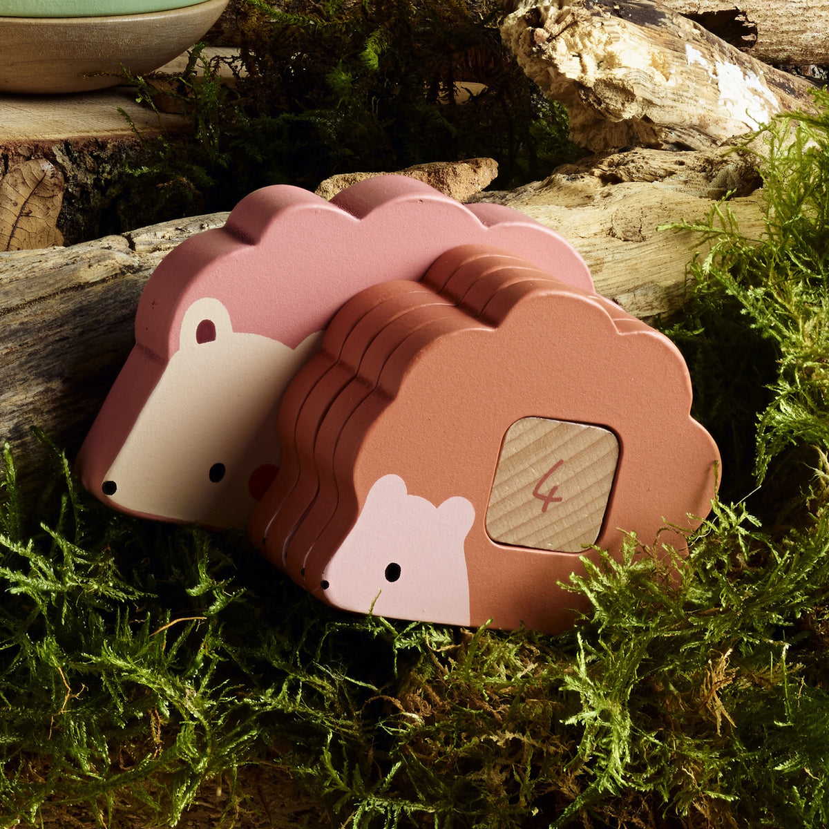 Vilac wooden hedgehog toy with numbered stacking blocks on a mossy forest floor background.