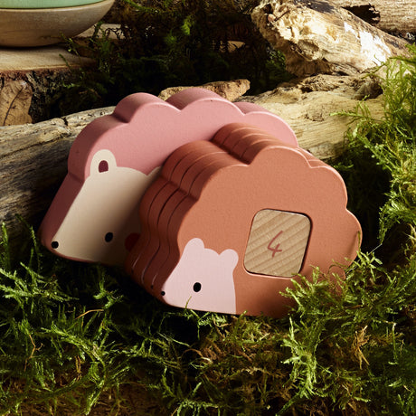 Vilac wooden hedgehog toy with numbered stacking blocks on a mossy forest floor background.