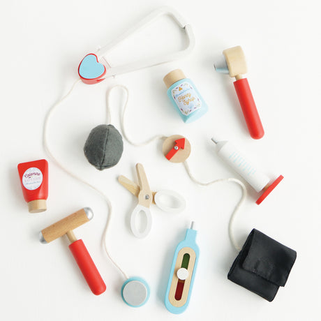 Wooden doctor roleplay tools and medical accessories flat lay on a white background.