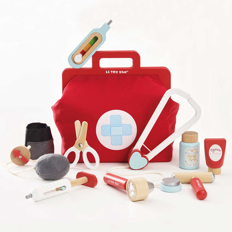 Red wooden doctor bag surrounded by various wooden medical roleplay accessories and tools, with a play thermometer resting on top of the bag.