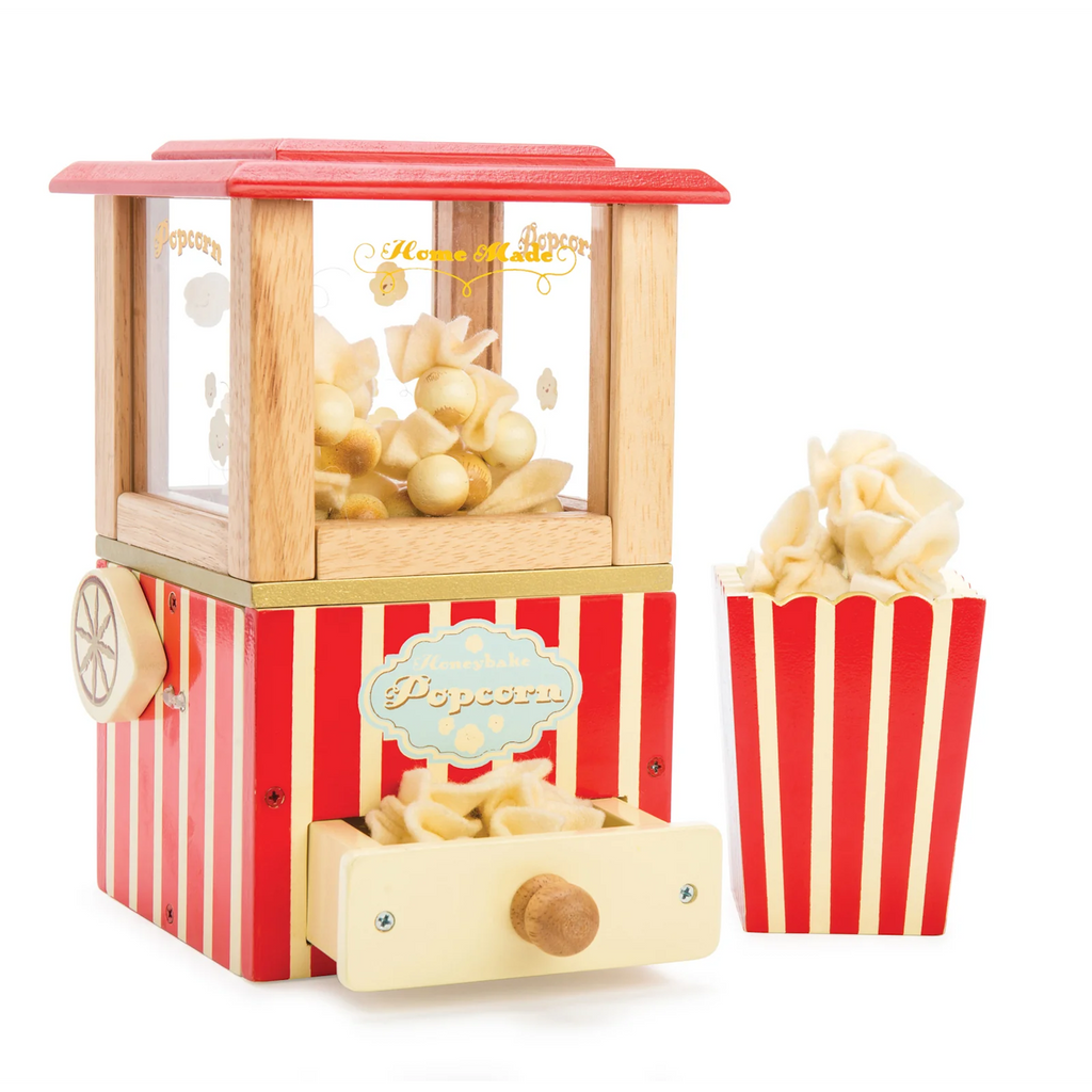 Toy popcorn machine with red and white stripes and wooden accents, containing plush popcorn. Accompanied by a matching striped popcorn box. Playful and nostalgic.