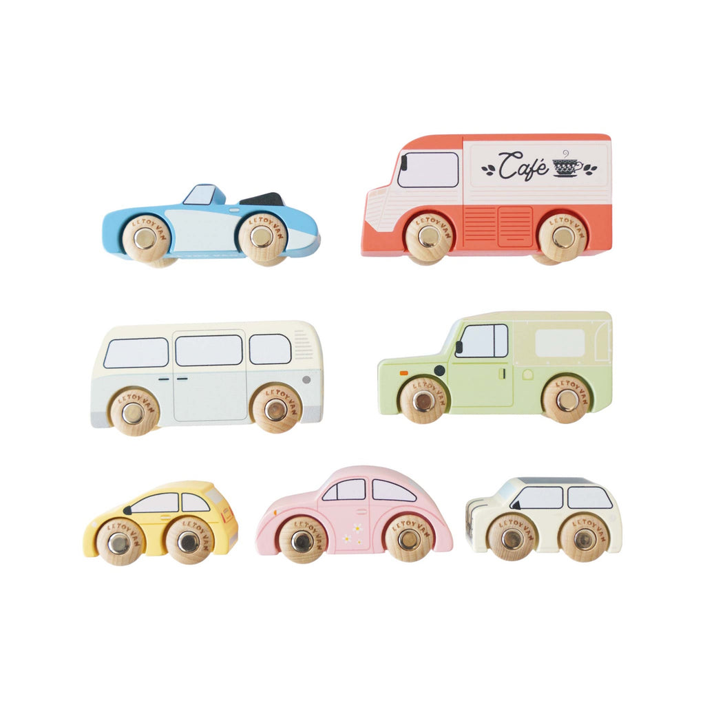 Colorful wooden toy vehicles on display include a red café truck, green SUV, blue sports car, yellow taxi, pink car, cream bus, and beige camper.