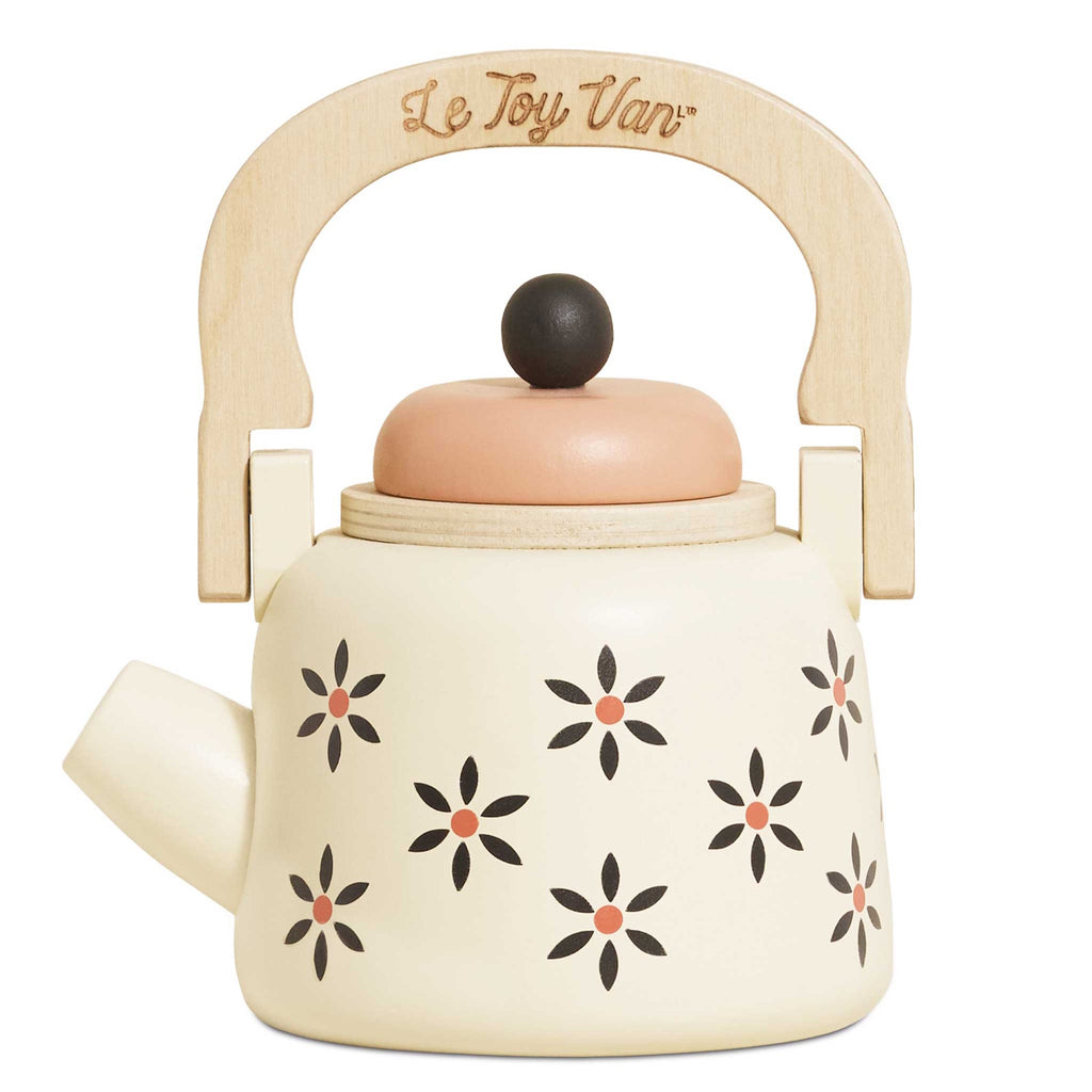 Toy teapot with a wooden handle and cream body, featuring black and orange floral patterns. The lid is peach-colored, creating a playful and nostalgic vibe.