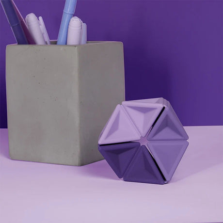 Purple silicone hexaflexagon fidget toy upright on a desk beside a concrete pen holder.