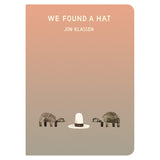 Book cover for We Found a Hat by Jon Klassen featuring two turtles looking at a tall white hat on a tan gradient background.