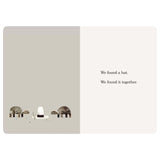 Two turtles stand next to a tall white hat with a black band. Text says, "We found a hat. We found it together."