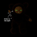 Werewolf plush doll glowing in the dark with bright green eyes and fangs against a black background.