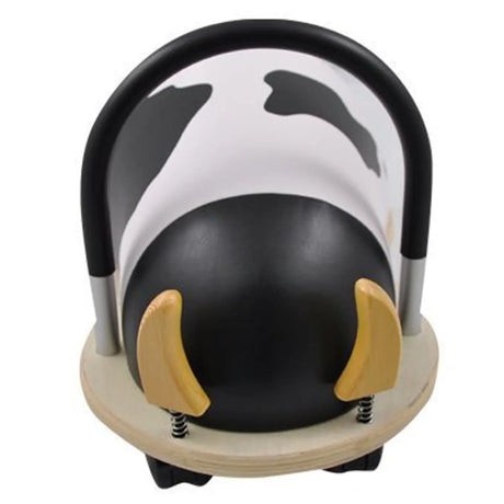 Front view of the cow Wheely Bug ride-on toy, showing its wooden horns on springs, black-and-white pattern, and handle.