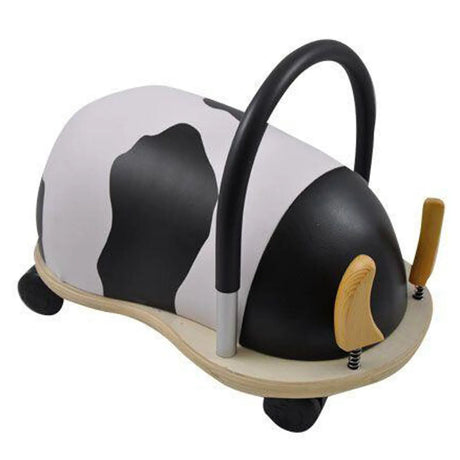 Rear-right view of the cow Wheely Bug ride-on toy, showing its curved black handle, black-and-white patterned body, and wooden base.