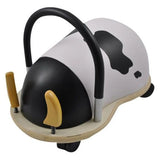 Side-profile view of the cow Wheely Bug ride-on toy, showing its curved black handle, black-and-white patterned body, and spring-mounted wooden horns.