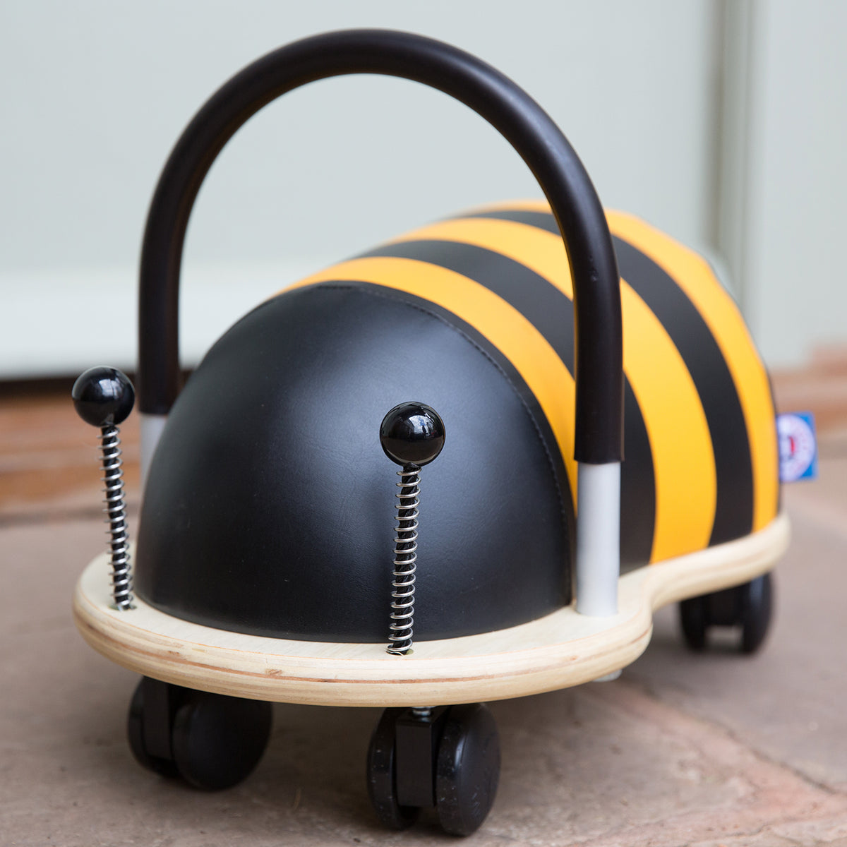 Plush bumblebee Wheely Bug ride on toy with spring antennae and a wooden base on wheels.