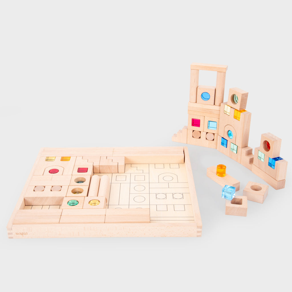 A large collection of wooden construction blocks with embedded colorful gems, designed to encourage creative building, light play, and sensory exploration.