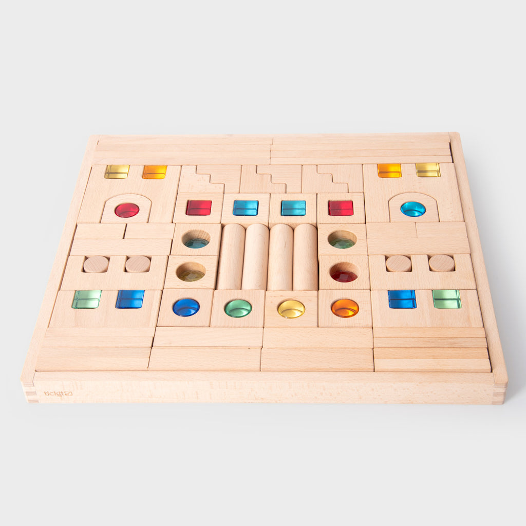 A large collection of wooden construction blocks with embedded colorful gems, designed to encourage creative building, light play, and sensory exploration.
